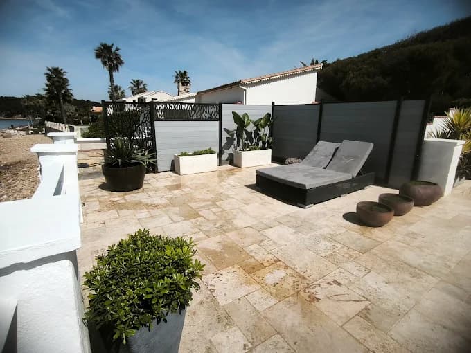 Terrasse en travertin face à la mer réalisée par Cyrus Paysage